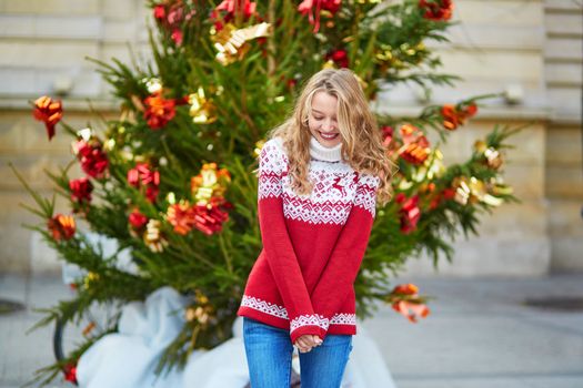 Girl with a brightly decorated Christmas tree in Paris
