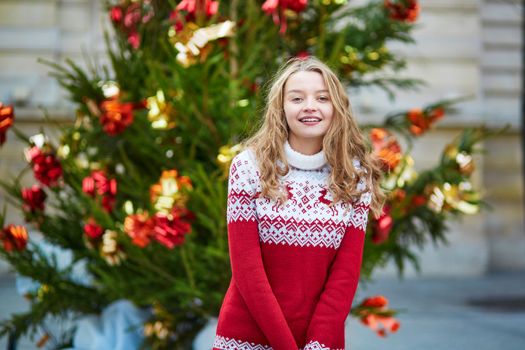 Girl with a brightly decorated Christmas tree in Paris