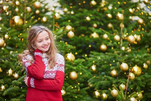 Girl with a brightly decorated Christmas tree in Paris