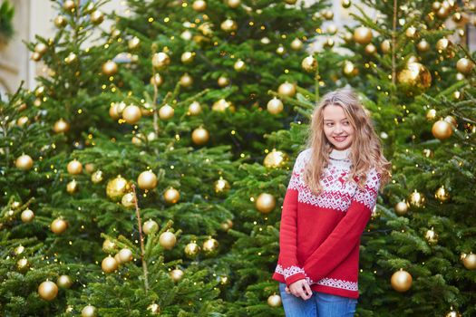 Cheerful young woman on a street of Paris decorated for Christmas