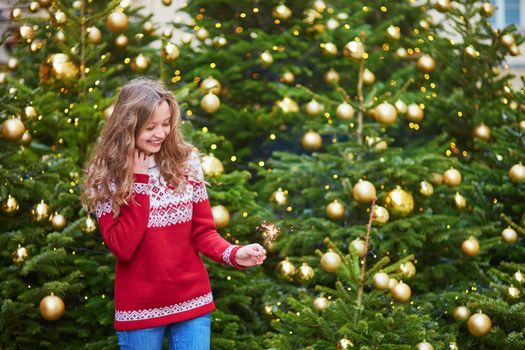 Cheerful girl on a Parisian street decorated for Christmas