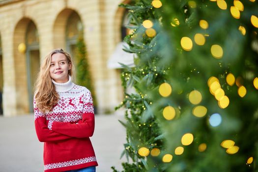 Girl with a brightly decorated Christmas tree in Paris