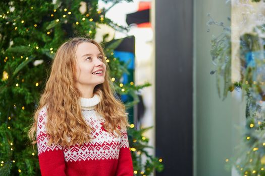 Young girl looking at Parisian shop-windows decorated for Christmas
