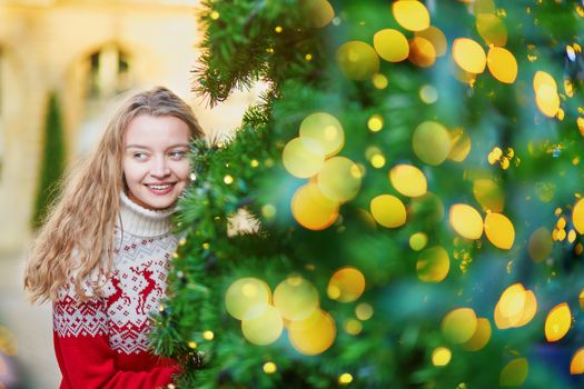 Girl with a brightly decorated Christmas tree in Paris