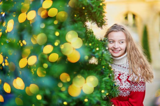 Girl with a brightly decorated Christmas tree in Paris