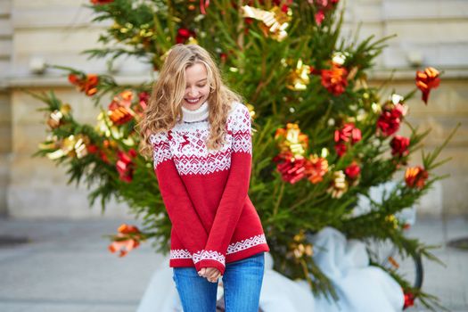 Girl with a brightly decorated Christmas tree in Paris