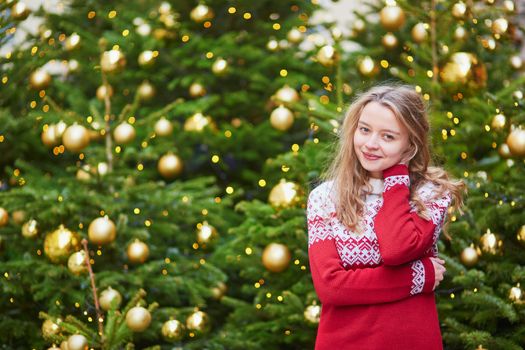 Cheerful young woman on a street of Paris decorated for Christmas
