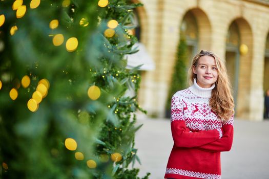 Cheerful young woman on a street of Paris decorated for Christmas
