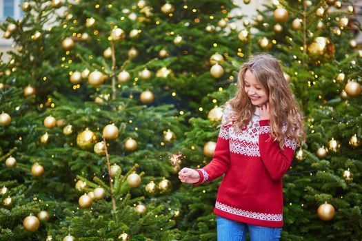 Cheerful girl on a Parisian street decorated for Christmas