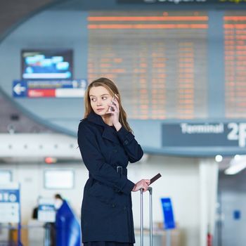 Young woman in international airport near large information display