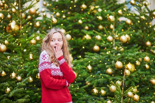 Astonished girl with a brightly decorated Christmas tree
