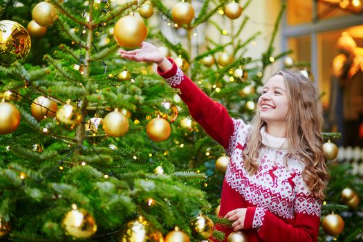 Girl decorating Christmas tree with golden balls