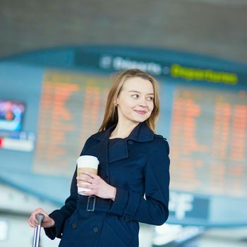 Young woman in international airport near large information display