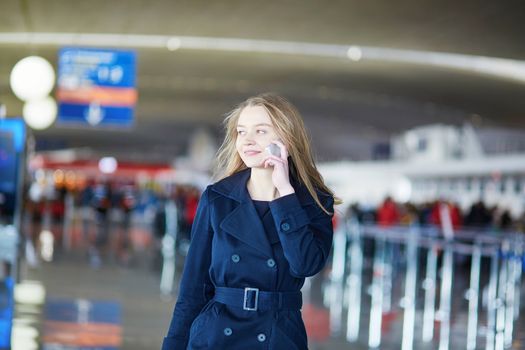 Young woman in international airport, walking with her luggage