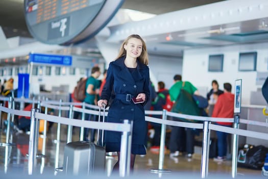 Young woman in international airport, walking with her luggage