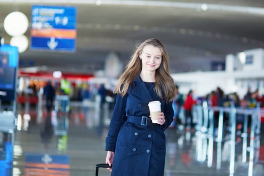 Young woman in international airport, walking with her luggage