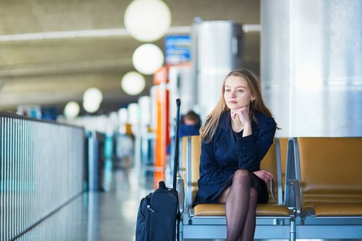 Young woman in international airport, waiting for her flight