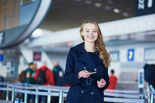 Young woman in international airport, giving her passport to an officer