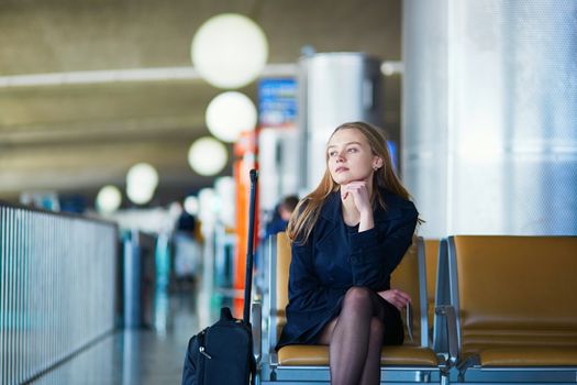 Young woman in international airport, waiting for her flight