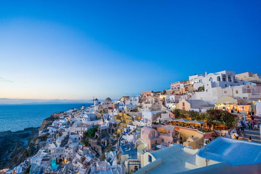 Picturesque view, Old Town of Oia or Ia on the island Santorini, white houses, windmills and church with blue domes at sunset, Greece