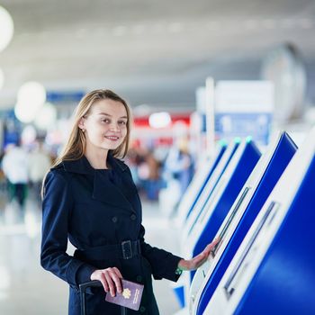 Young woman in international airport doing self check-in