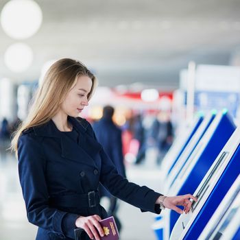 Young woman in international airport doing self check-in