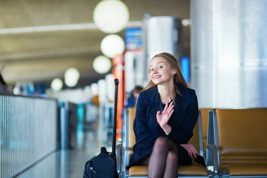 Young woman in international airport, waiting for her flight