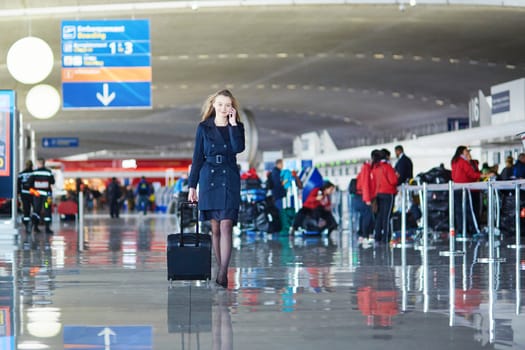 Young woman in international airport, walking with her luggage