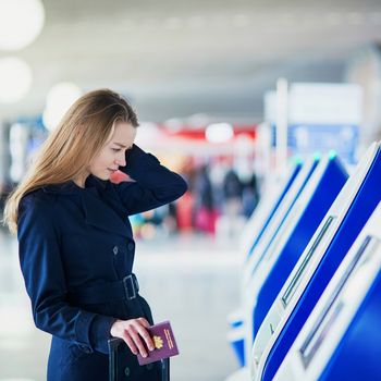Young woman in international airport doing self check-in