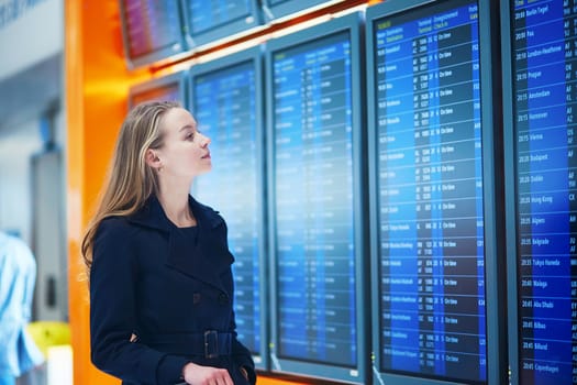 Young woman in international airport near the flight information board