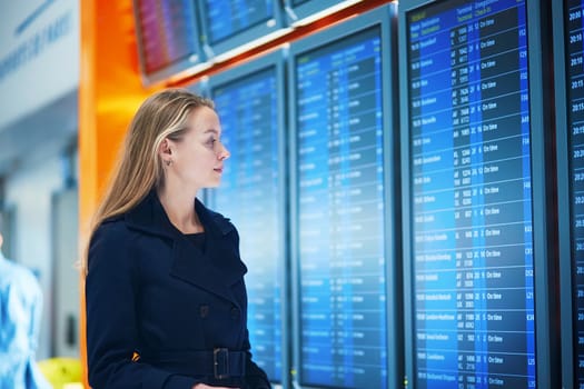 Young woman in international airport near the flight information board