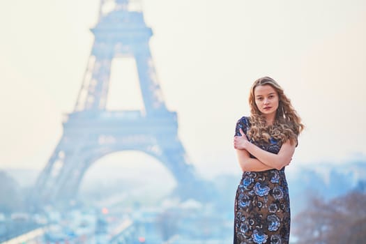 Beautiful elegant Parisian woman near the Eiffel tower at early morning