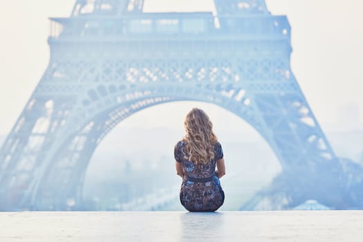 Beautiful elegant Parisian woman near the Eiffel tower at early morning