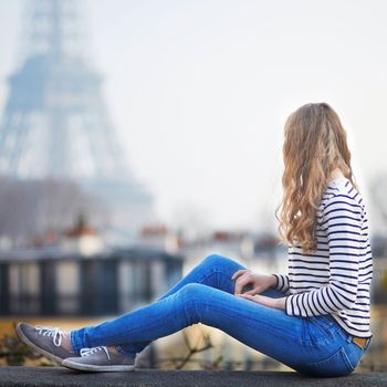 Happy young woman in Paris, near the Eiffel tower. Tourist in France, enjoying city view