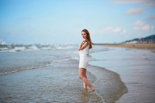 Beautiful young woman enjoying her vacation by ocean or sea, running and jumping in water. People on sea vacation concept
