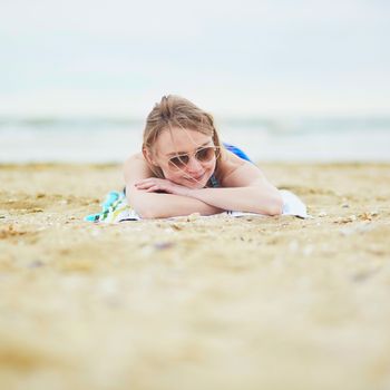 Beautiful young woman relaxing and sunbathing on sand beach