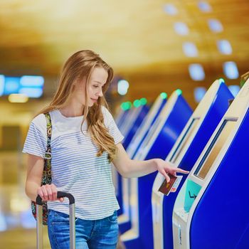 Young woman in international airport doing self check-in