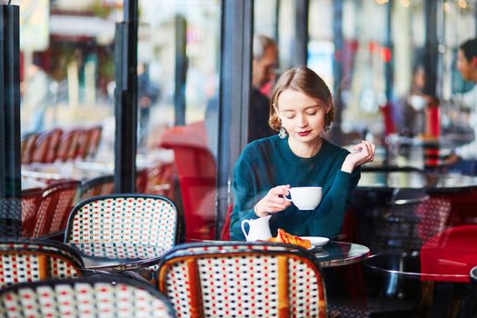 Young elegant woman drinking coffee in traditional cafe in Paris, France