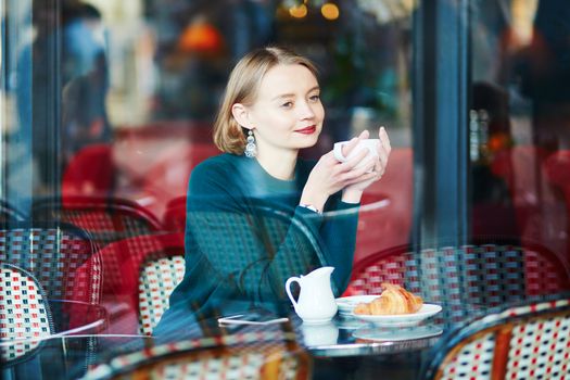 Young elegant woman drinking coffee in traditional cafe in Paris, France