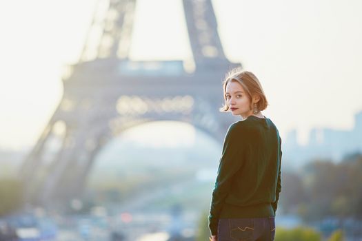 Beautiful young girl in Paris near the Eiffel tower at morning