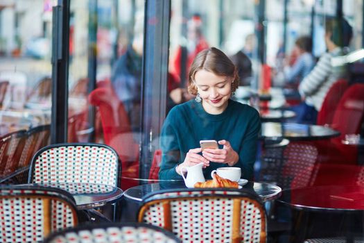 Elegant French woman drinking coffee in Parisian cafe near the window