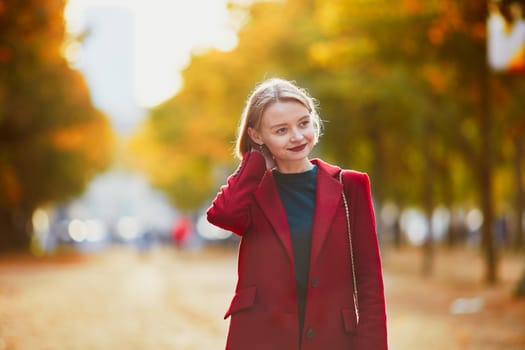 Beautiful young woman with bunch of colorful autumn leaves walking in park on a fall day