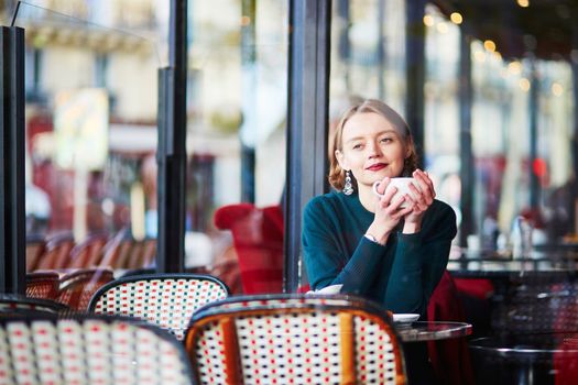 Young elegant woman drinking coffee in traditional cafe in Paris, France