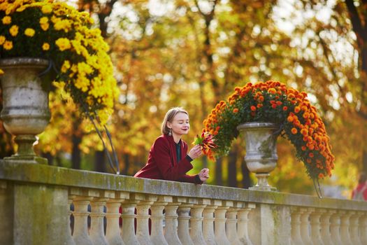 Beautiful young woman with bunch of colorful autumn leaves walking in park on a fall day. Luxembourg garden, Paris, France