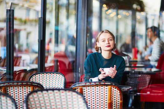 Young elegant woman drinking coffee in traditional cafe in Paris, France