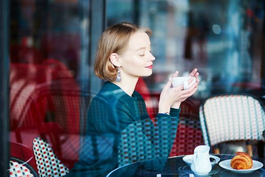 Young elegant woman drinking coffee in traditional cafe in Paris, France