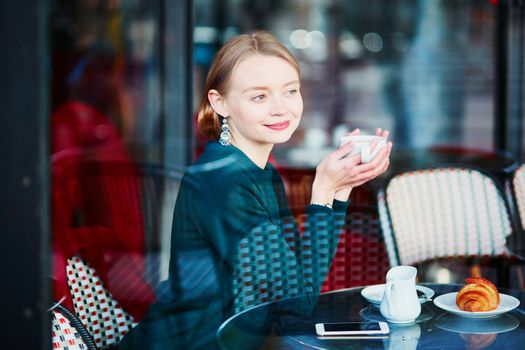 Young elegant woman drinking coffee in traditional cafe in Paris, France