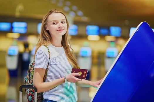 Young woman in international airport doing self check-in