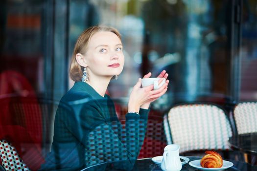 Young elegant woman drinking coffee in traditional cafe in Paris, France