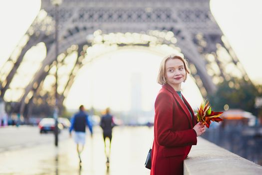 Beautiful young French woman drinking coffee near the Eiffel tower in Paris on a fall or spring day